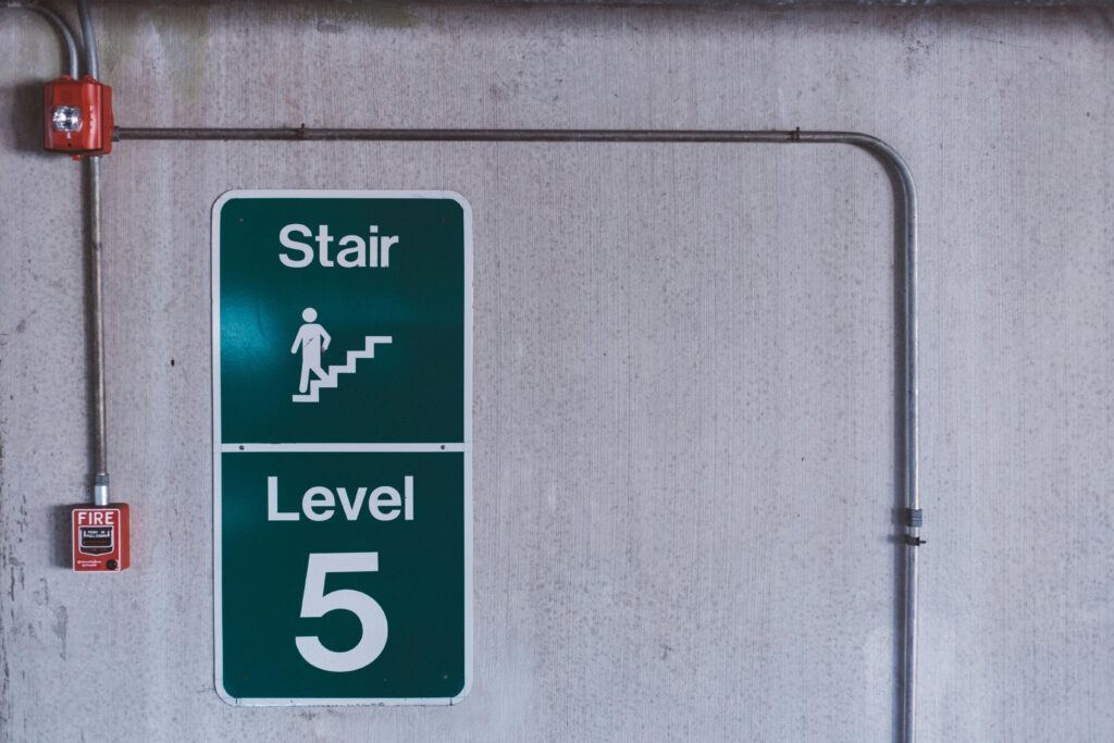 pexels-photo-103592-103592 A fire alarm and stair sign on level 5 in an industrial indoor setting.